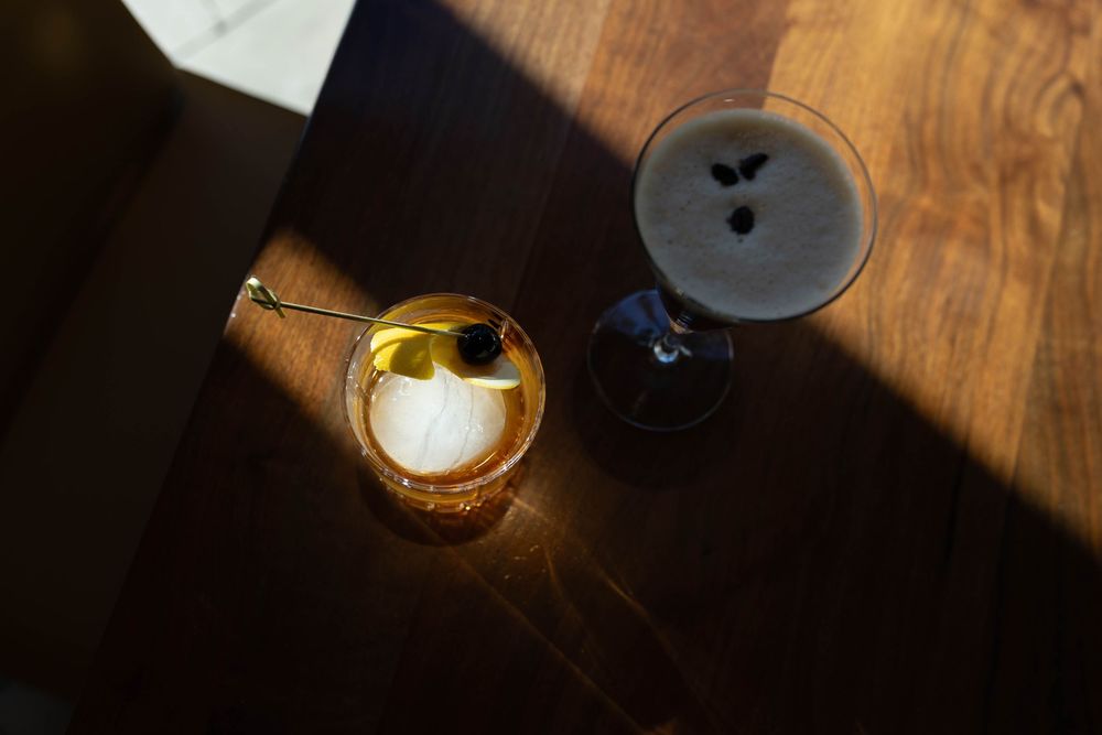 Moody lighting on wooden table with drinking glasses and candles.