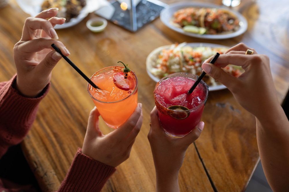 Colorful cocktails and drinks arranged on a wooden table at a restaurant.