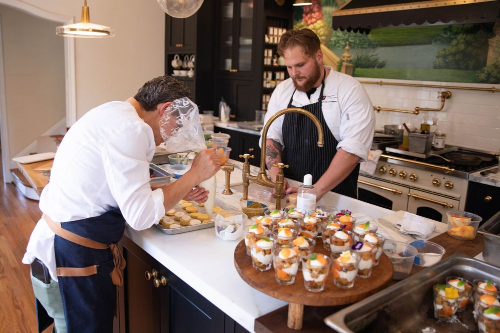 Chefs preparing gourmet dishes in professional kitchen with mood lighting.