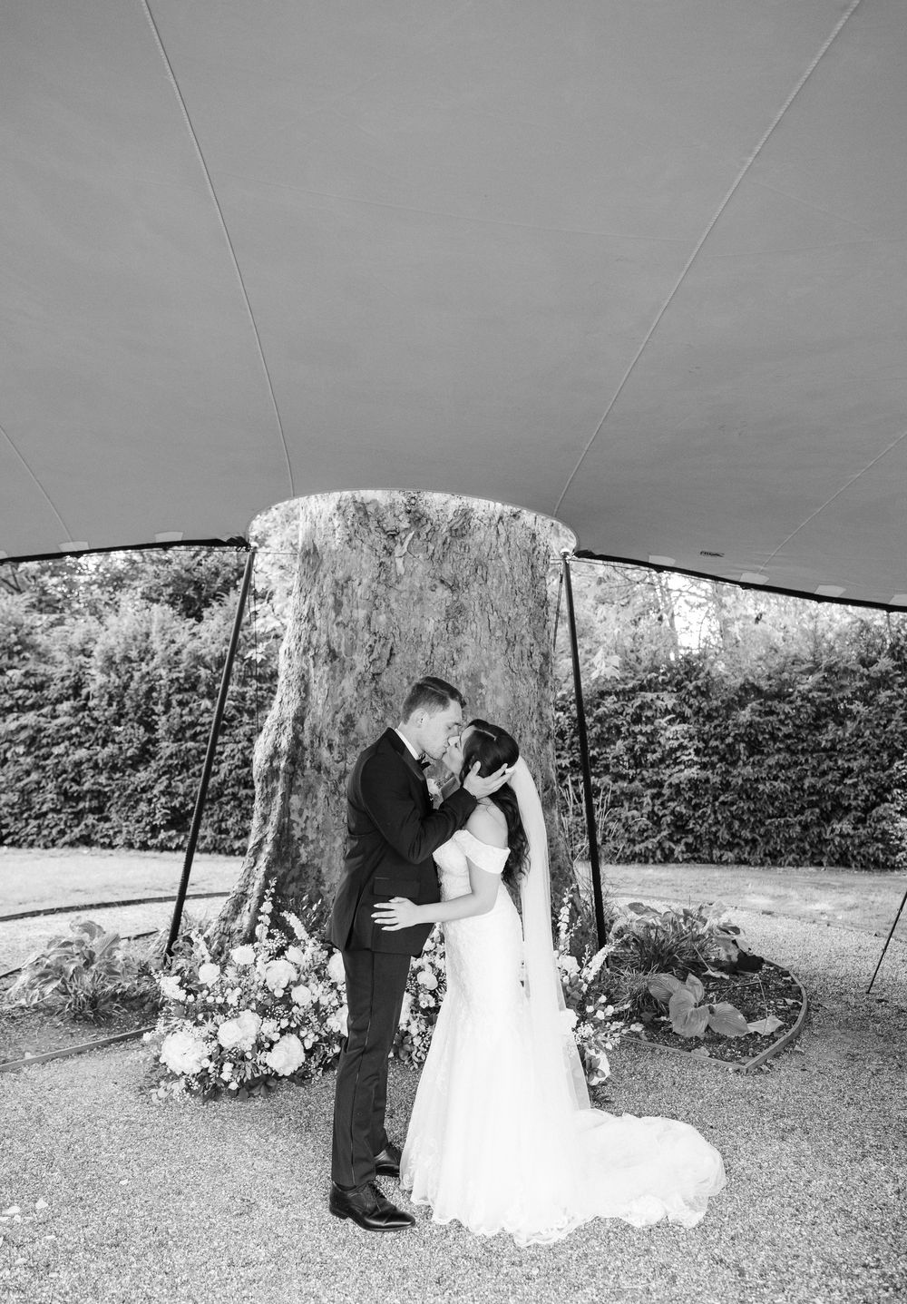Black and white panoramic sequence of a romantic moment between newlyweds in a garden setting.