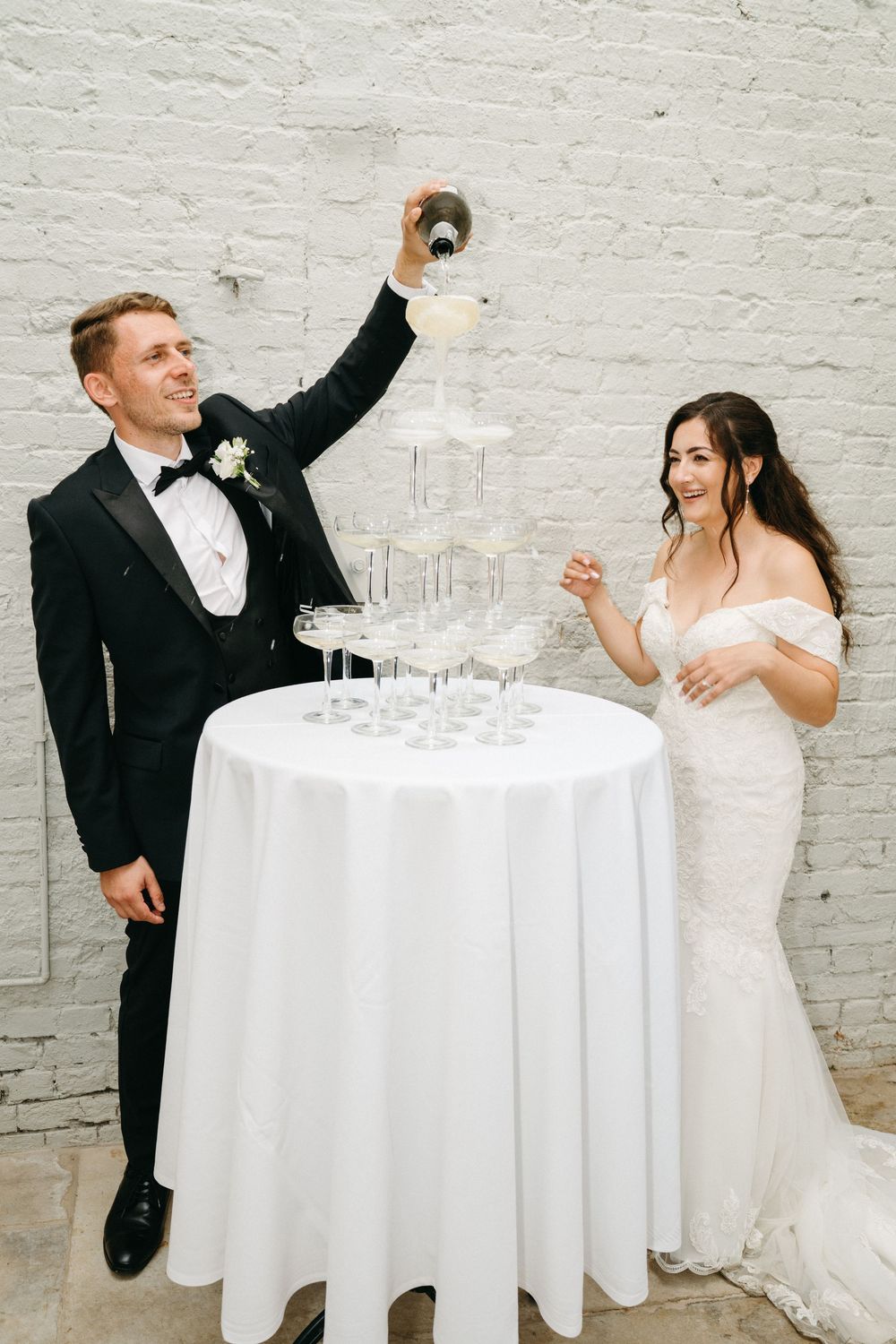 Newlyweds perform a playful dance sequence next to an elegant white cocktail table. Taken by modern editorial wedding photographer.