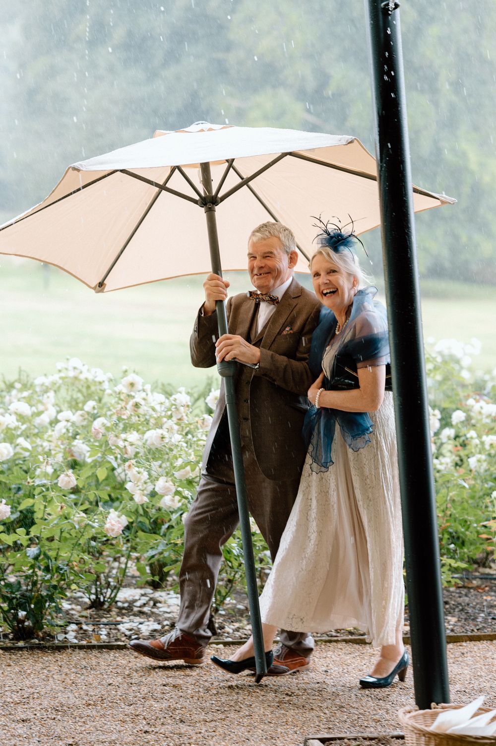 A couple laughing and sharing playful moments together with parasols in a garden setting.