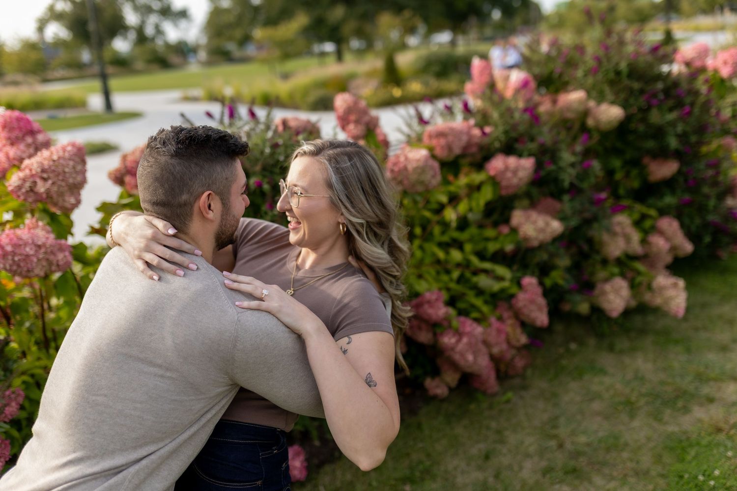 engagement shoot with man dipping his fiancé by the hydrangea flowers at Rosevelt park, MI in front of michigan central station