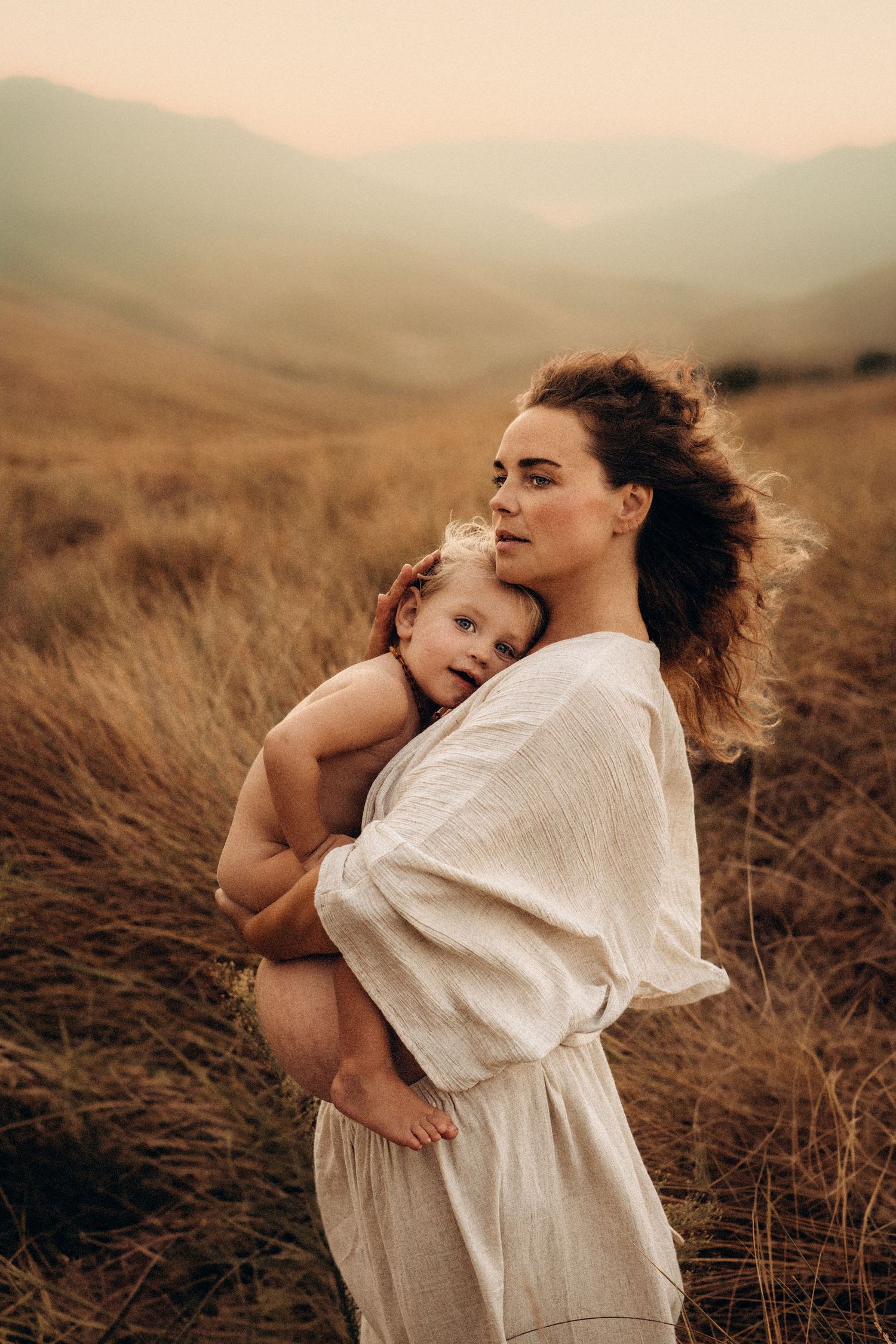 Mother and child embrace tenderly in a golden wheat field during sunset, creating an intimate moment against nature's backdrop. Javea photo