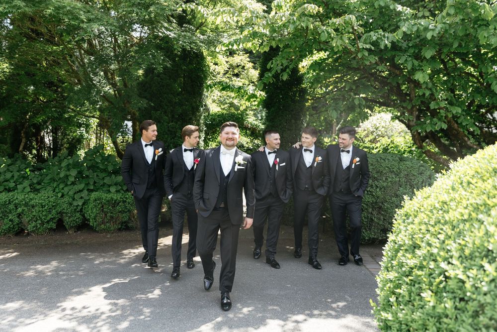 A sequence of wedding party photos showing groomsmen walking in formal black suits along a garden path.