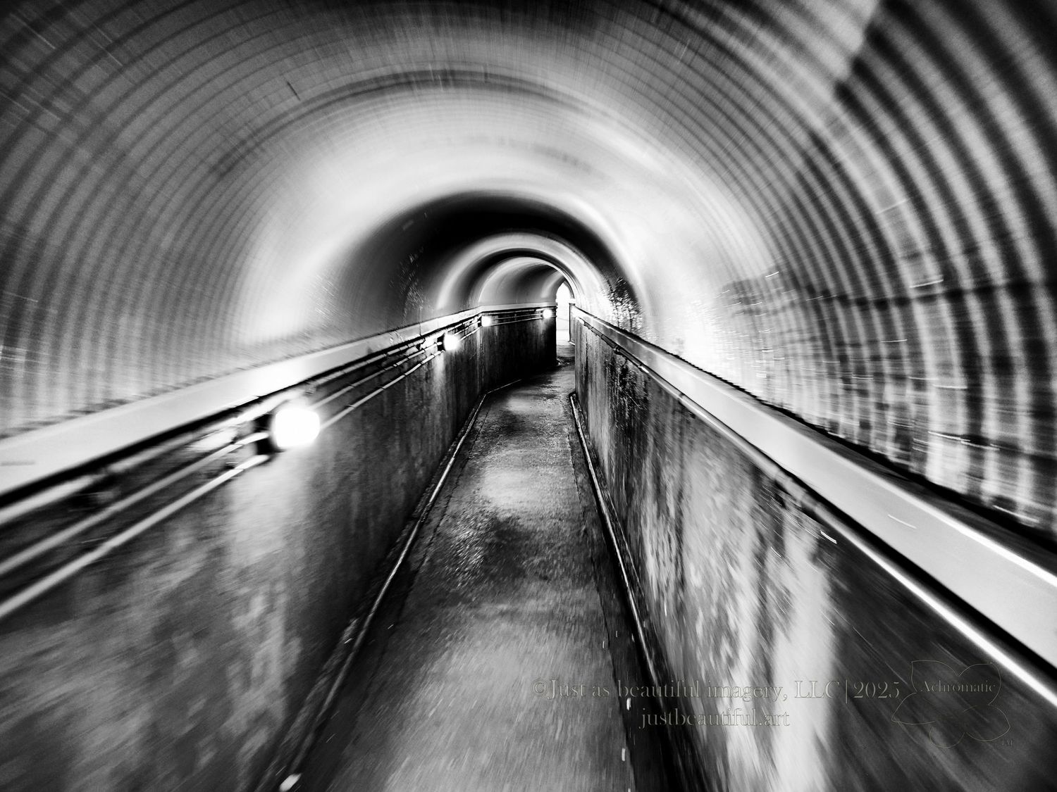 Achromatic photo of a lighted tunnel.