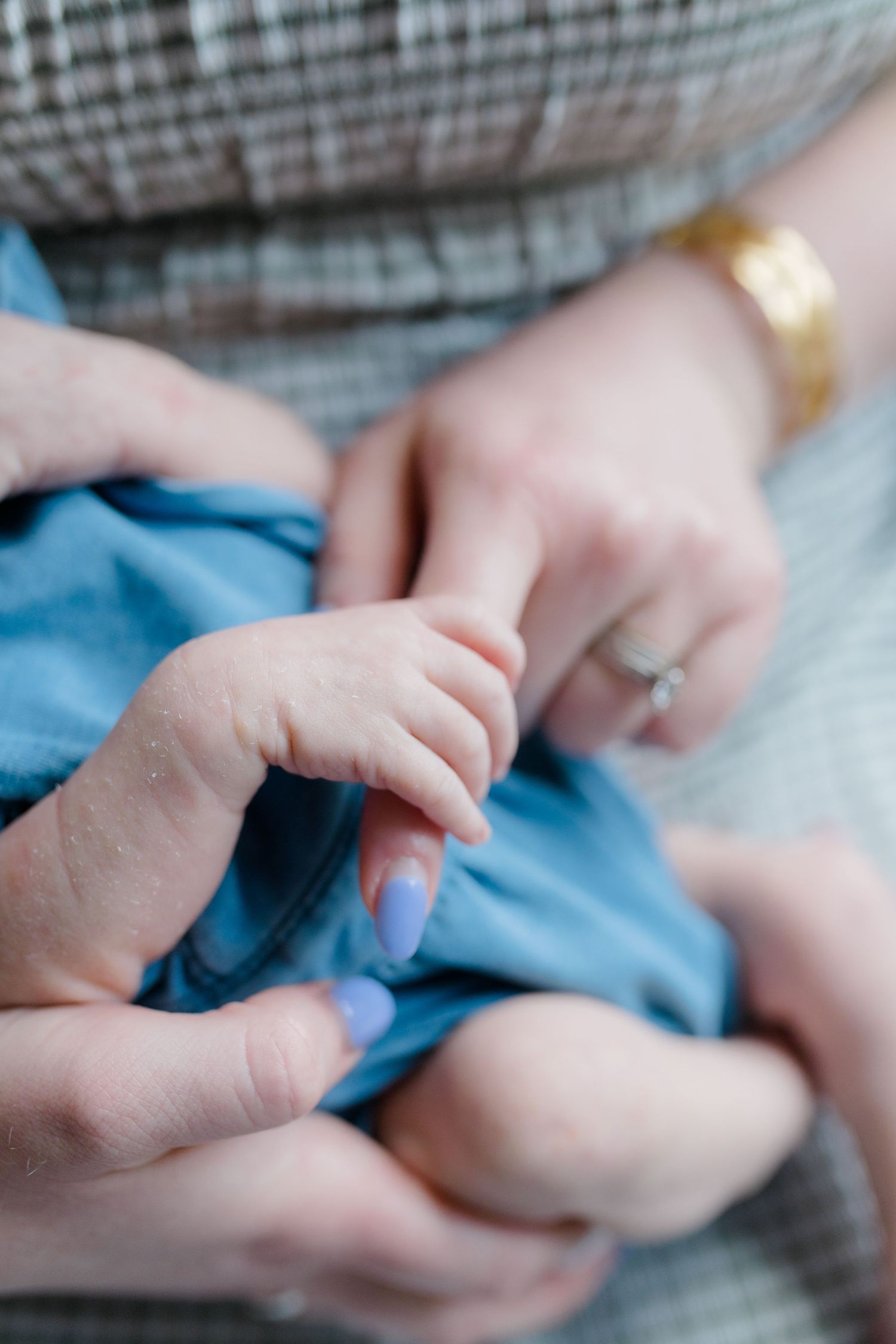 Close-up of tiny baby hands grasping against blue fabric.