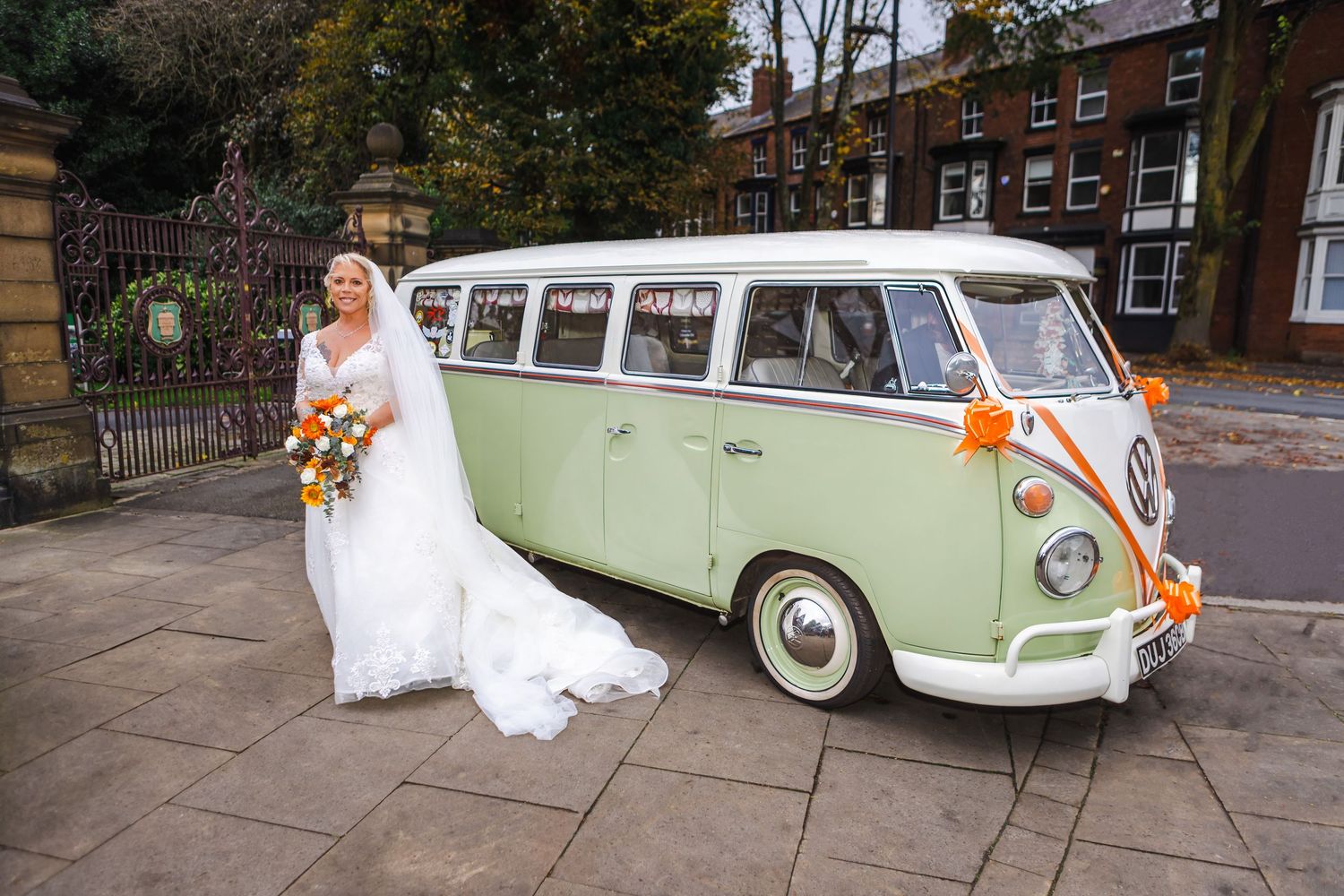 Classic vintage Volkswagen van parked on a tree-lined street with bridal party photos being taken.