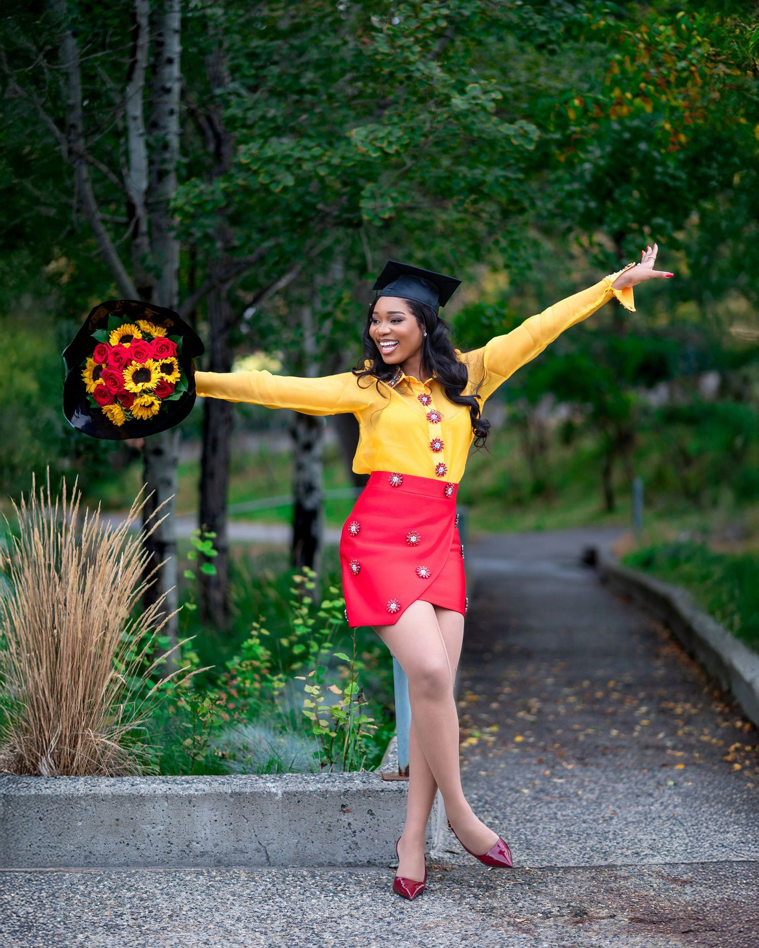 Playful graduation photoshoot on pathway with yellow and red outfit.