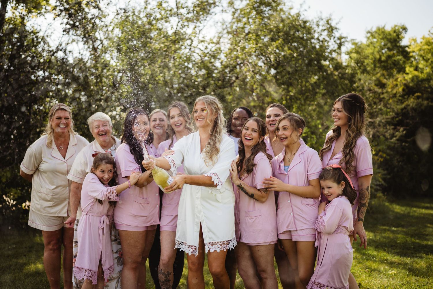 Group of friends celebrating together outdoors in matching pink and white outfits during golden hour.