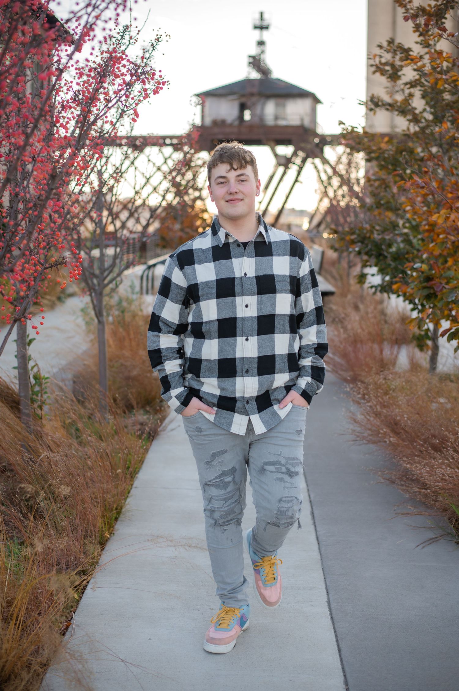 Portrait photography on a path showing a casual outfit with plaid shirt, jeans and yellow sneakers in autumn scenery.