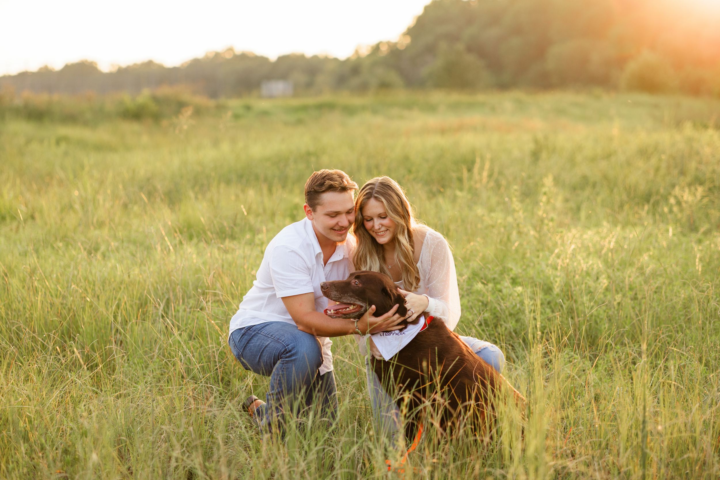 Couple shares playful moments together in a sunlit grassy field during golden hour.