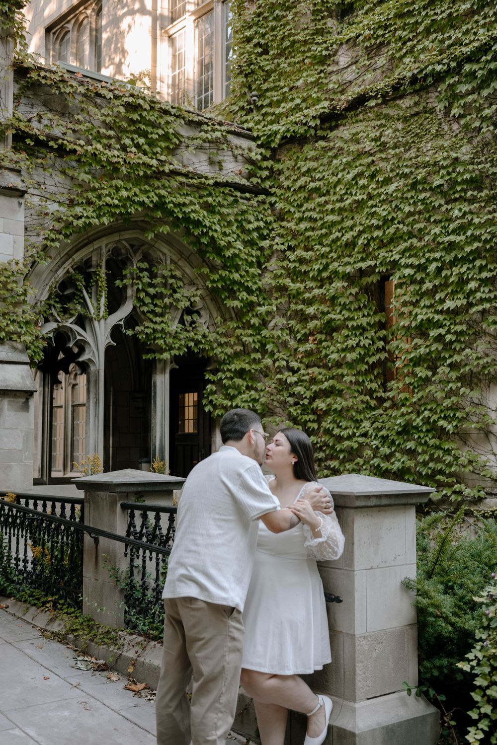 A romantic moment shared between a couple in an ivy-covered stone courtyard.