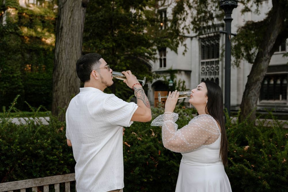 A couple in wedding attire dances together in a garden setting with trees and greenery in the background.
