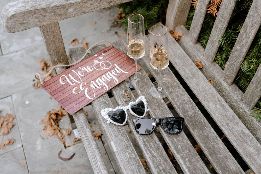 Wedding props and accessories including heart signs and sunglasses arranged on wooden bench slats.