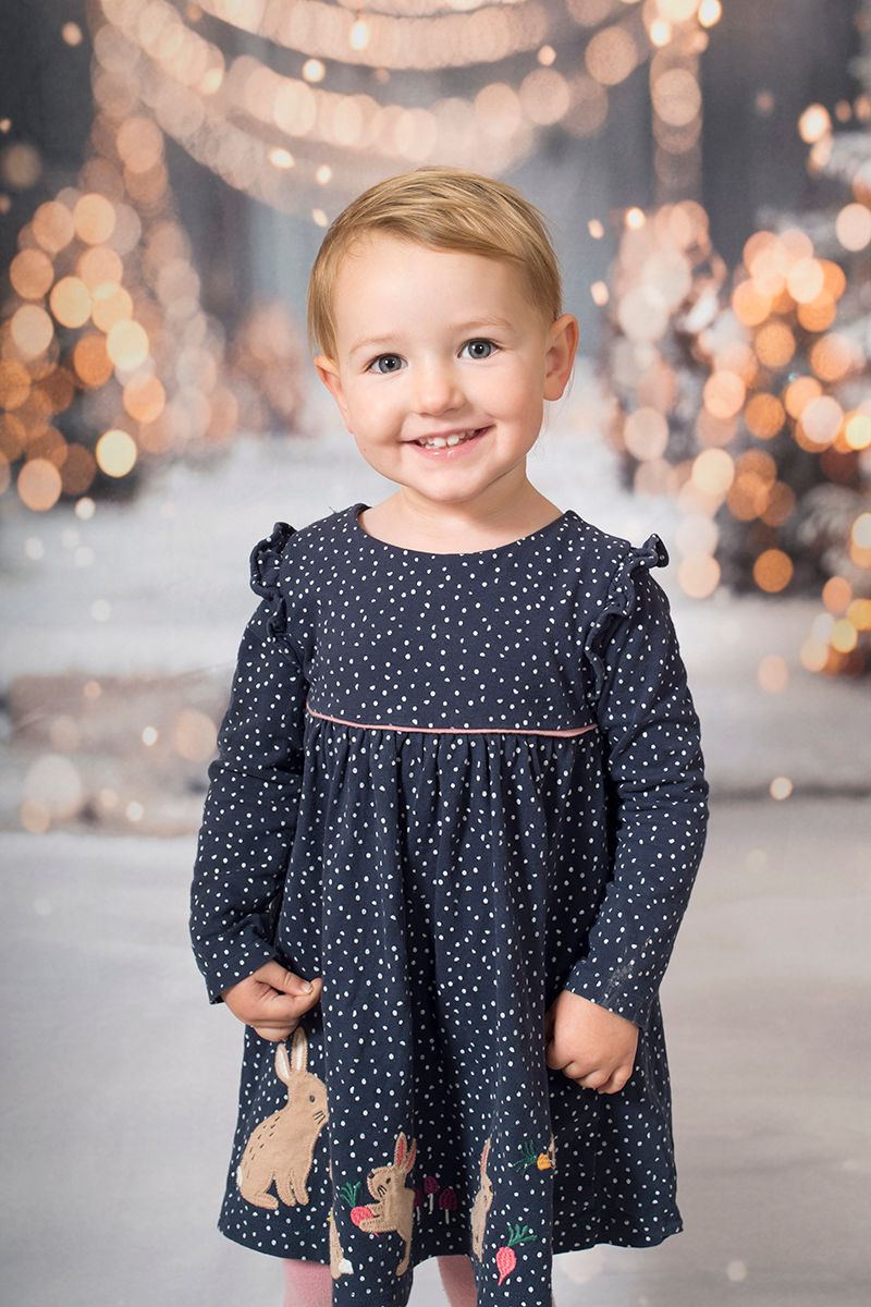 Individual portrait of a little girl surrounded by twinkling lights at the Christmas mini photoshoot pop-up, High Wycombe 2025.