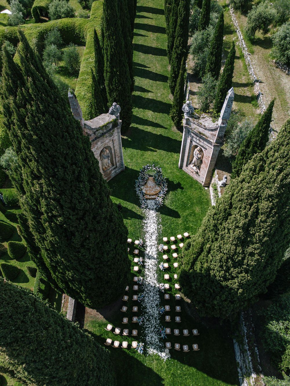 Aerial view of an Italian garden ceremony setup with cypress trees and symmetrical stone pathways.