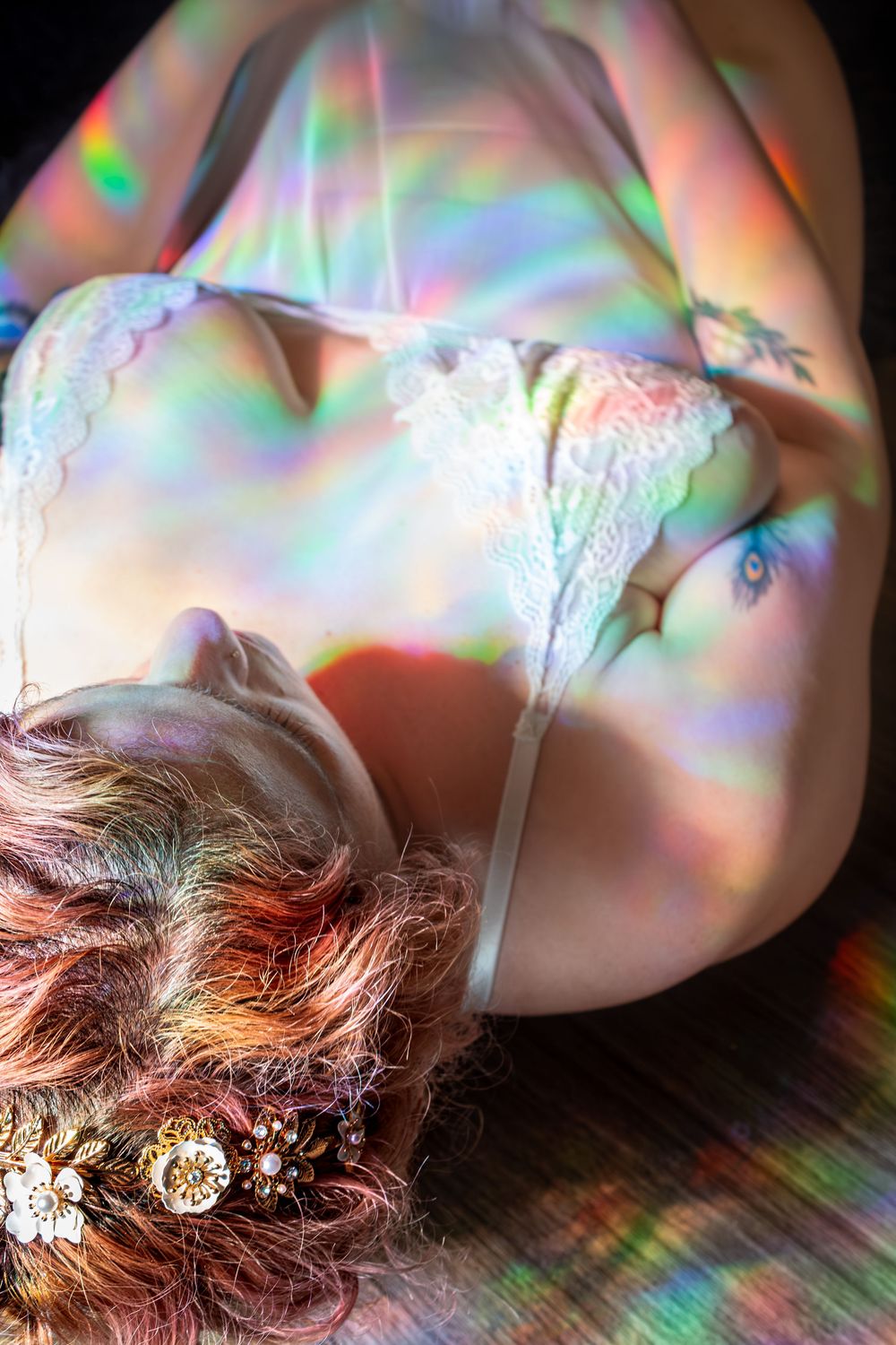 Dreamy overhead portrait with prismatic light effects, lace details, and hair adorned with crystal accessories.