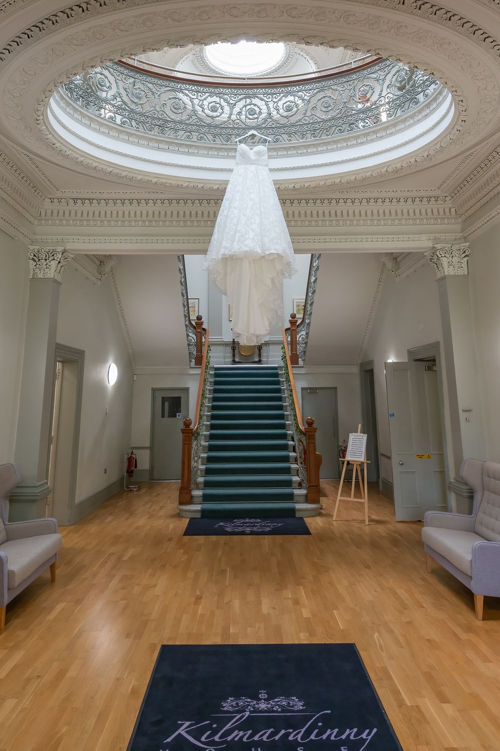 Elegant entrance hall with ornate domed ceiling, grand staircase, and hardwood floors.