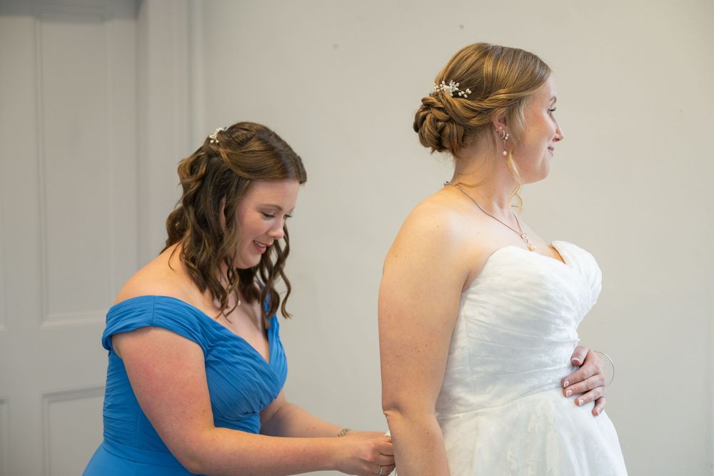 Wedding party members in blue and white dresses prepare for the ceremony indoors.