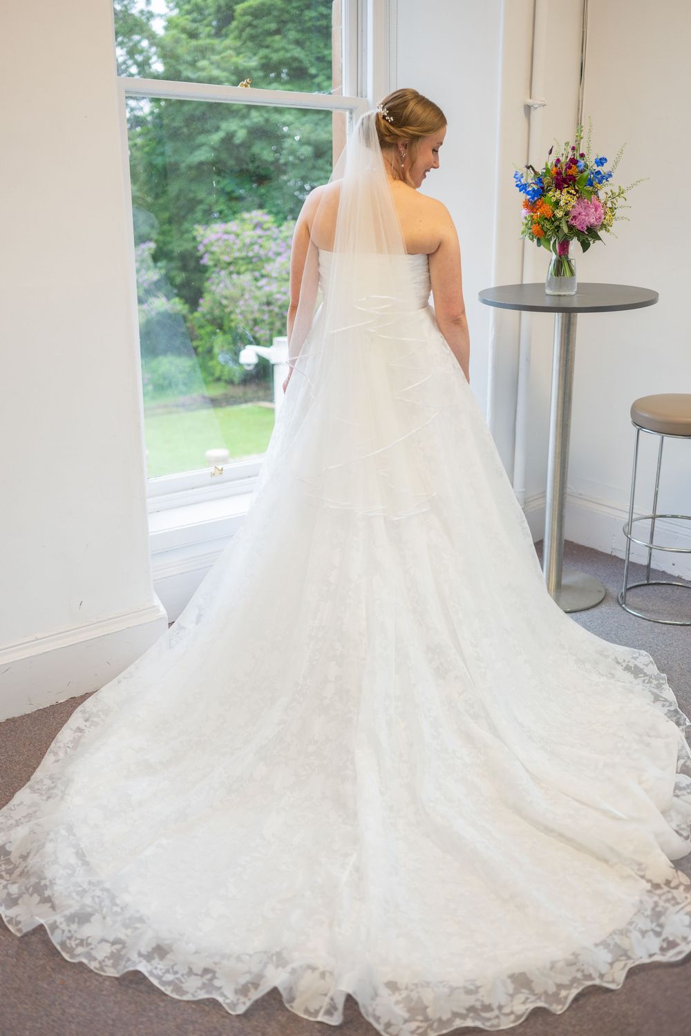 Full length view of an elegant white lace wedding gown with cathedral train.