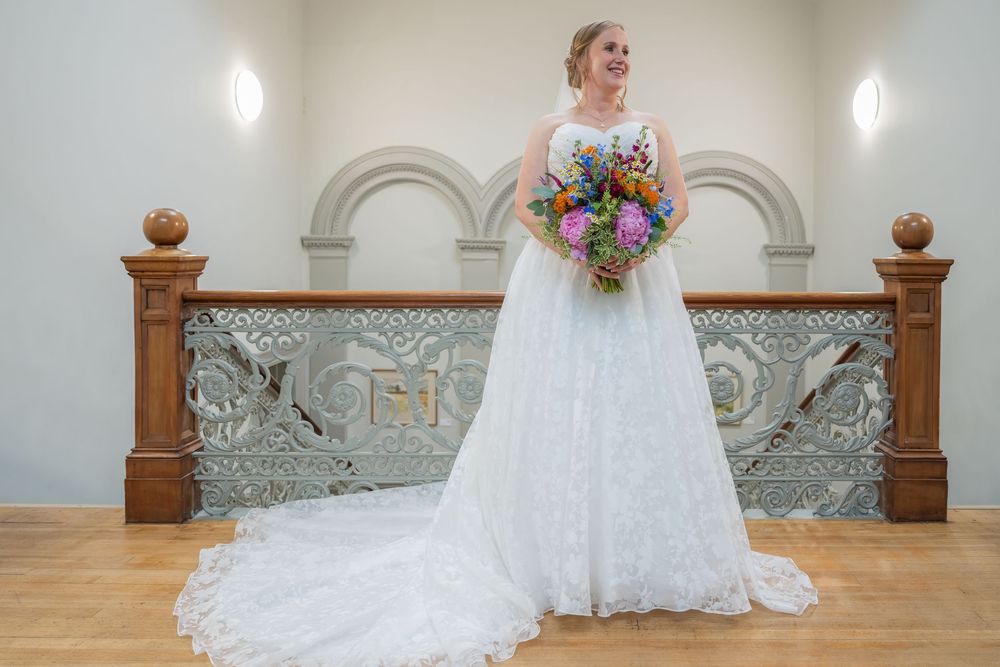 Elegant bridal portrait in a classic white wedding gown against ornate architectural details.