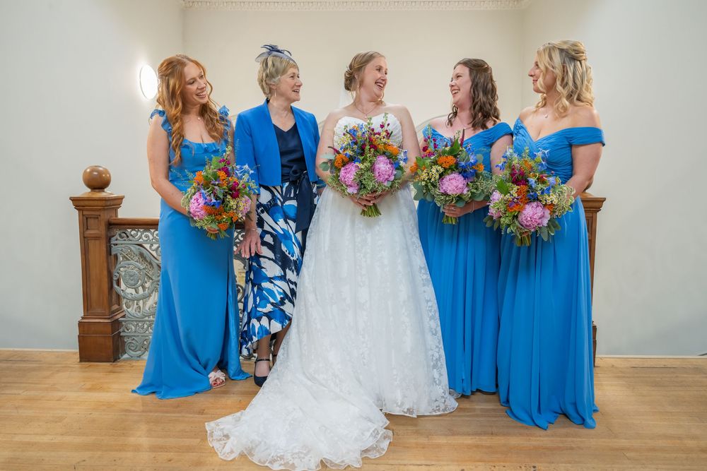 Wedding party in coordinating blue attire posing together indoors.
