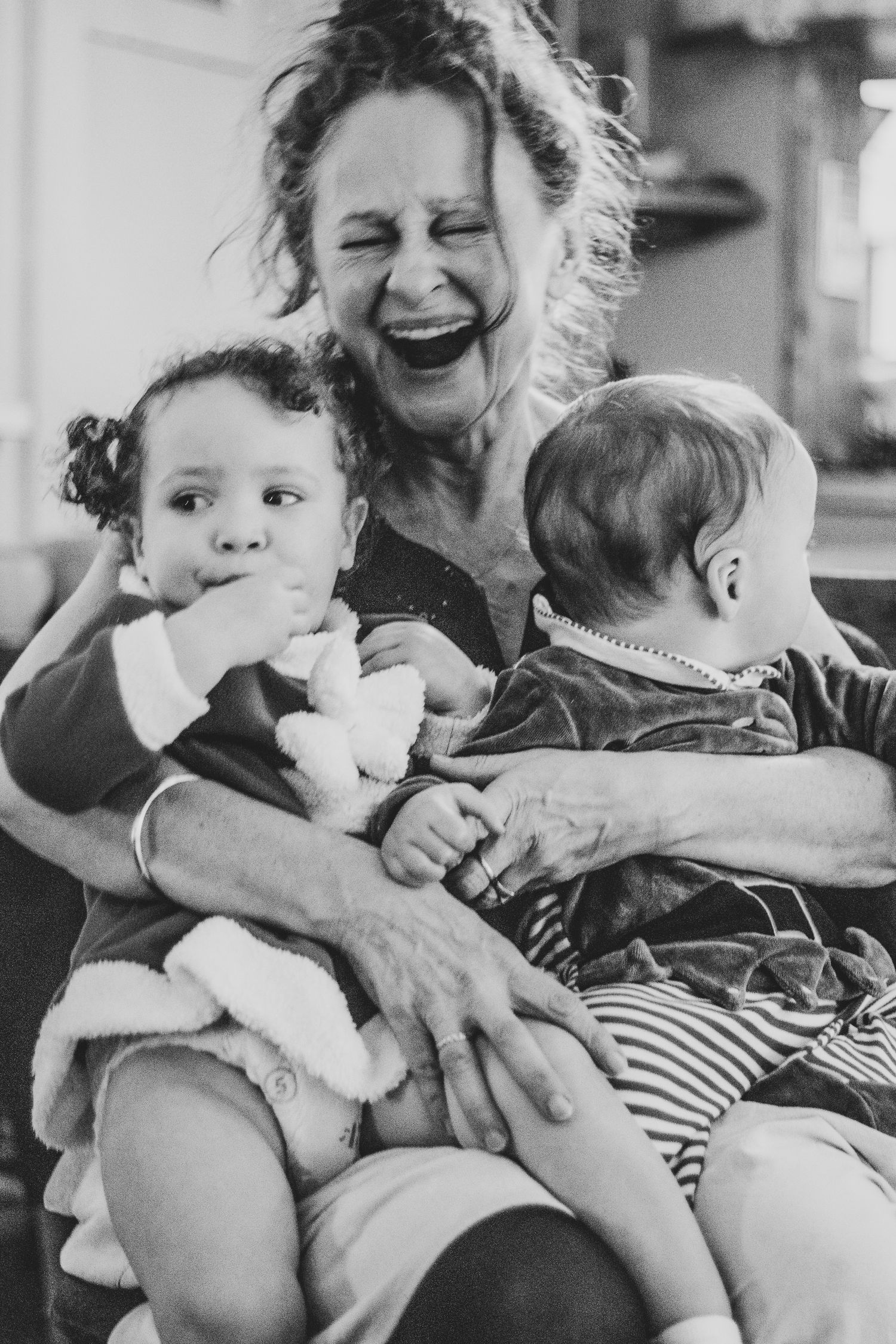 A nan laughing with her grandchildren in her home in Surrey — an emotive and intimate family session.