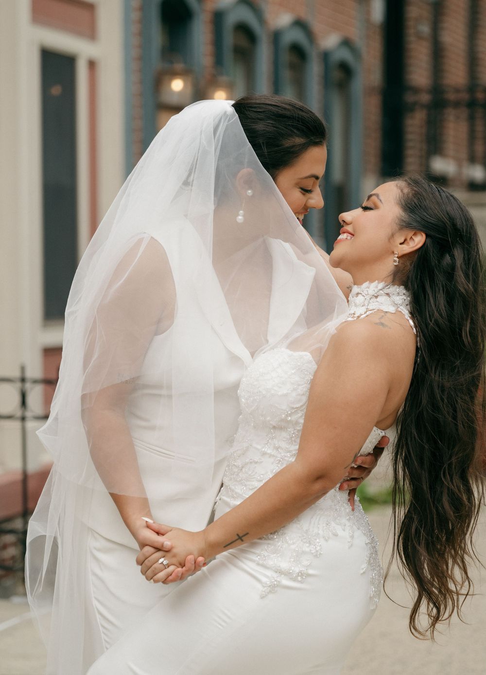Romantic wedding portraits against a brick building showing intimate embraces.