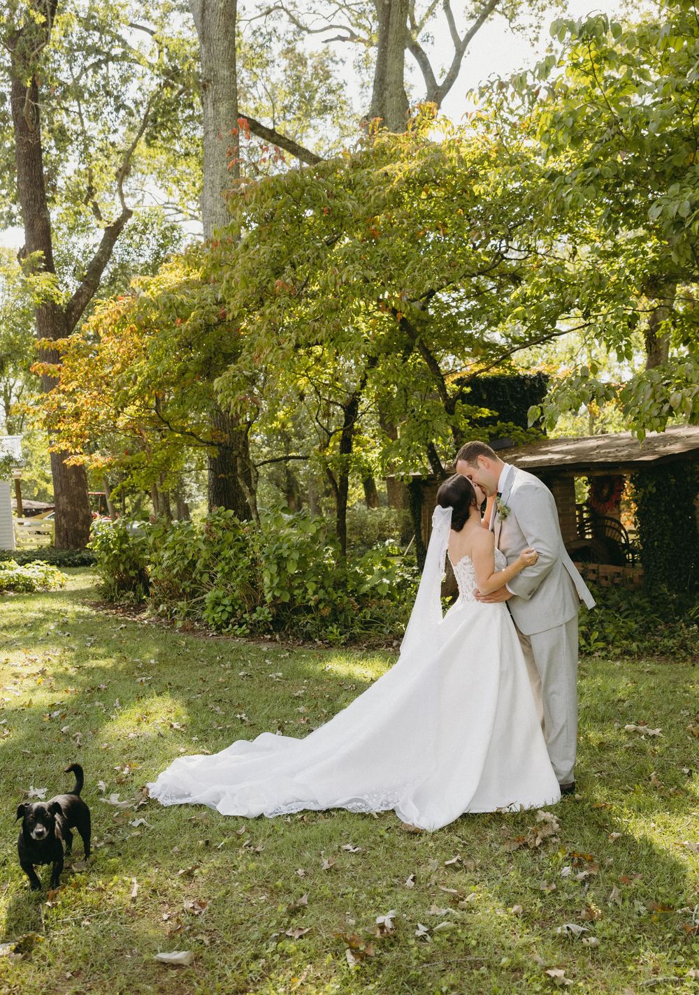 Wedding couple shares romantic moments in a sunlit garden with autumn trees.