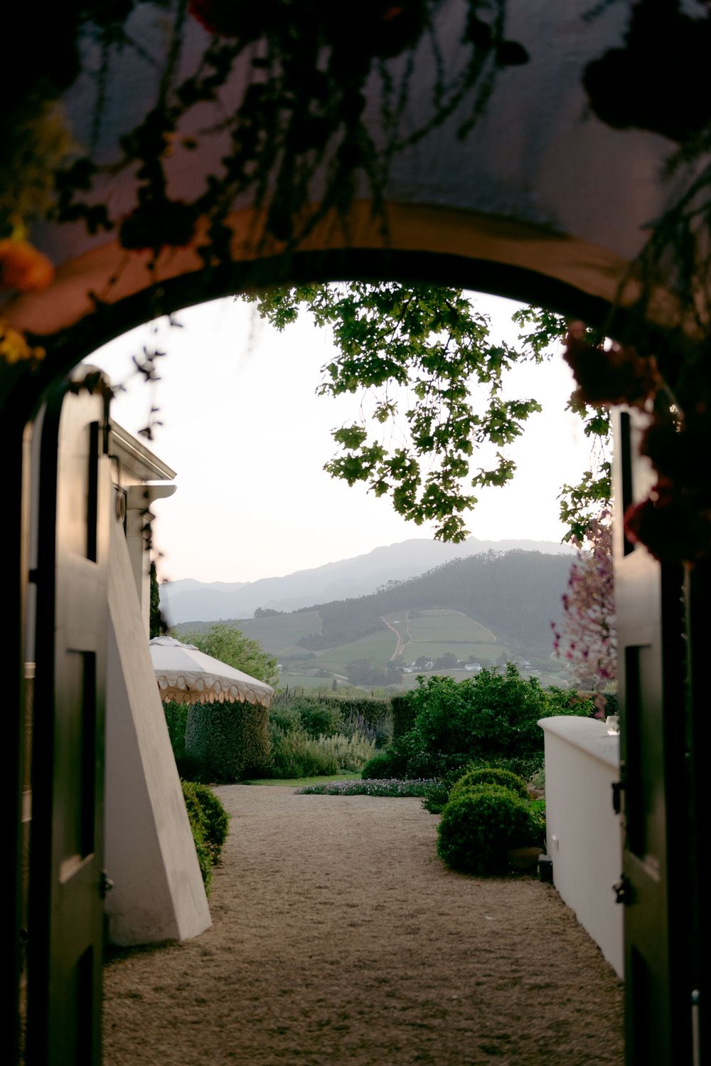 Archway entrance framing a scenic mountain view with manicured garden path and landscaping.
