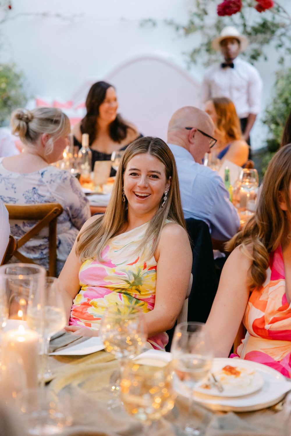 Elegant outdoor dinner party with glowing candles and floral centerpieces on a decorated table.