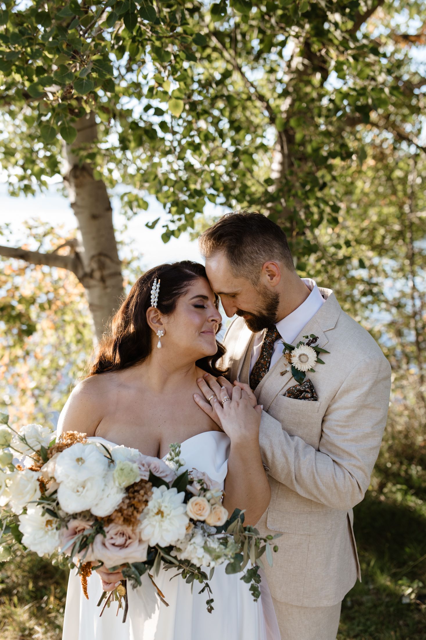 Intimate wedding portraits with white floral bouquet in a sunlit garden setting.