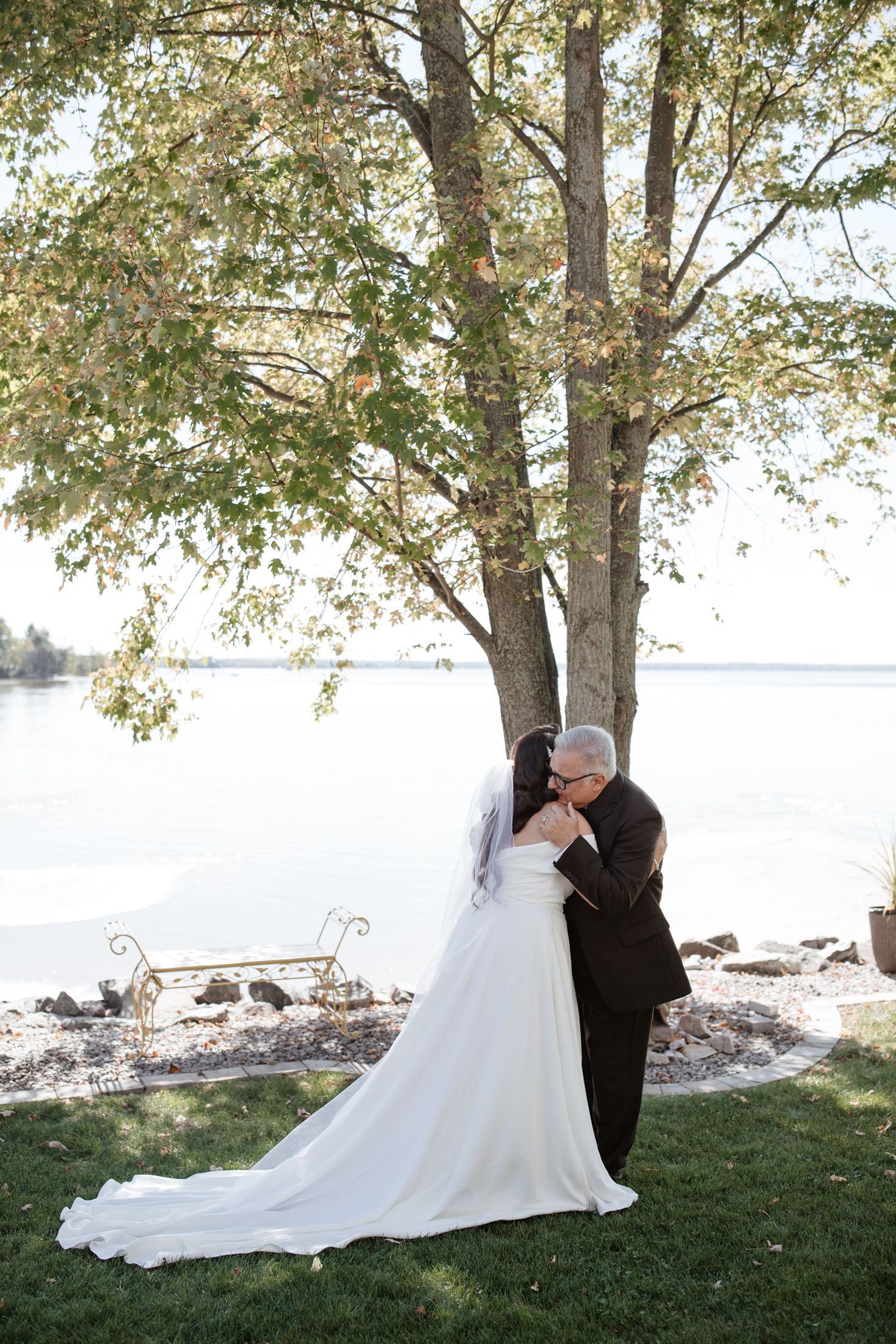 A sequence of romantic first look photos between a couple in a white wedding dress and black suit by trees.