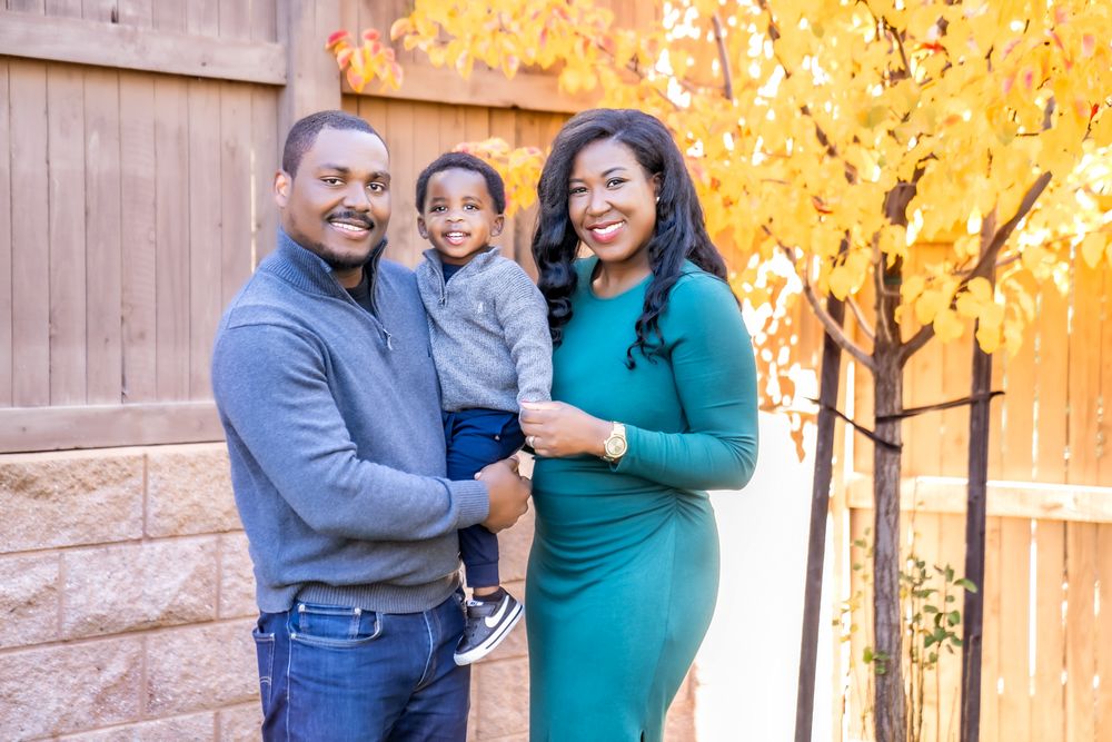 Family poses together for outdoor autumn portraits with glowing yellow foliage in the background.