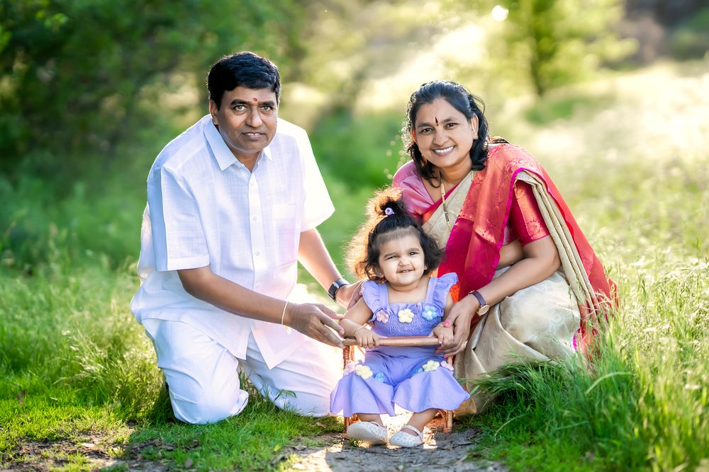 Family sitting together on grass in park during golden hour sunlight for outdoor portrait session.