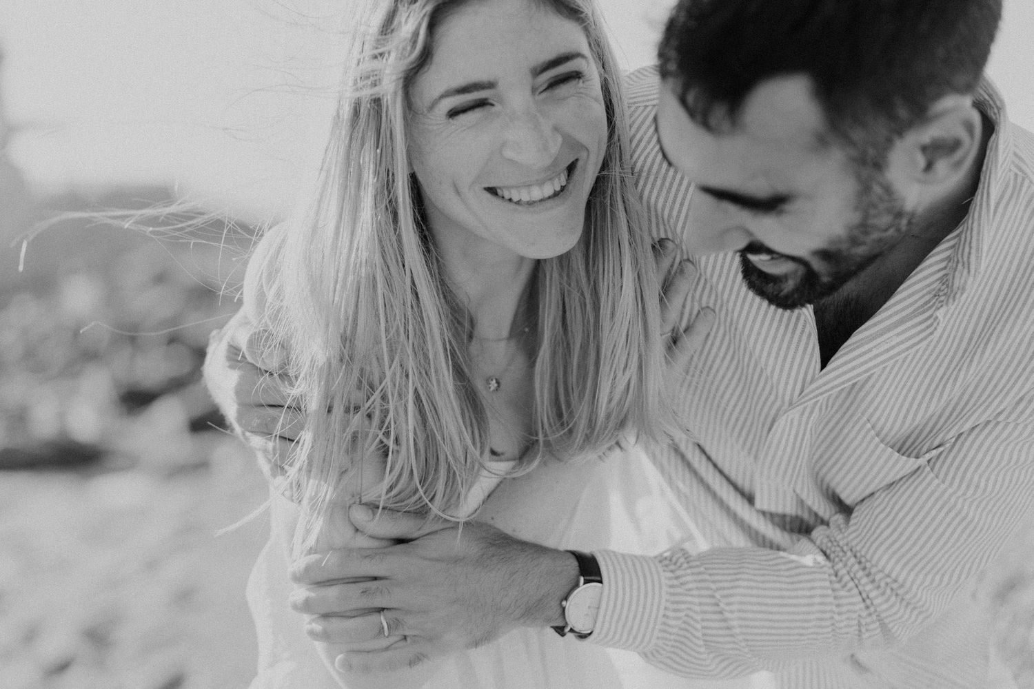 Candid engagement photo of Laure and Daniel laughing together in documentary style