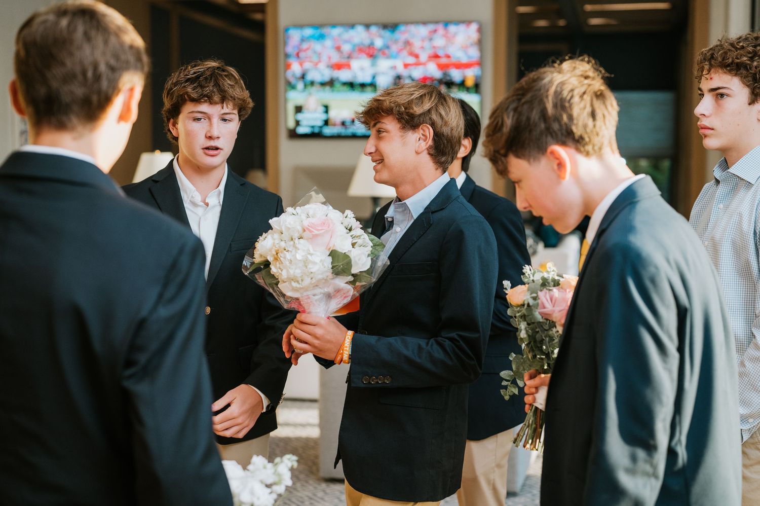 Wedding guests in dark suits mingle and socialize during a reception event.