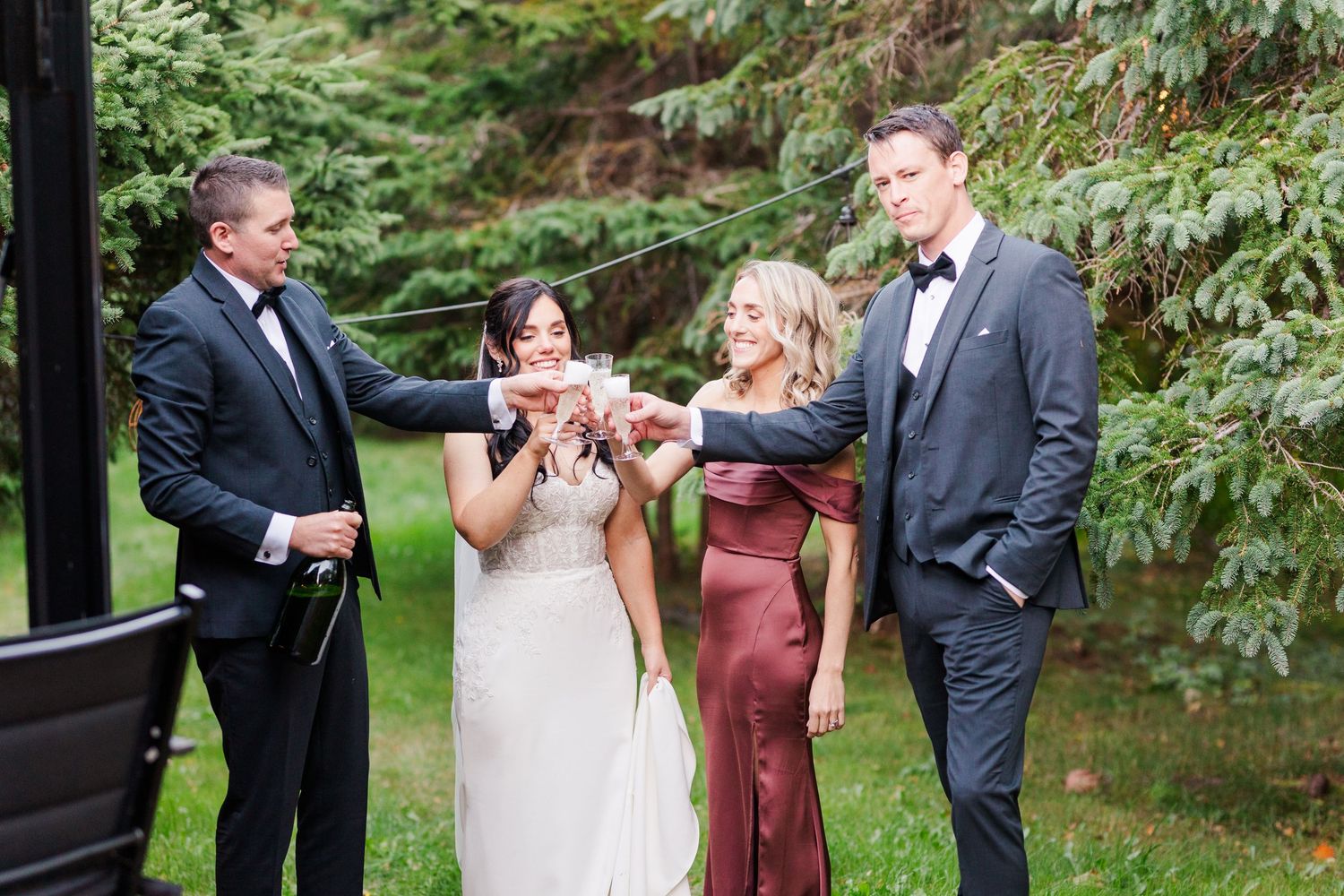 A group in formal attire celebrates at an outdoor garden wedding ceremony with a toast.