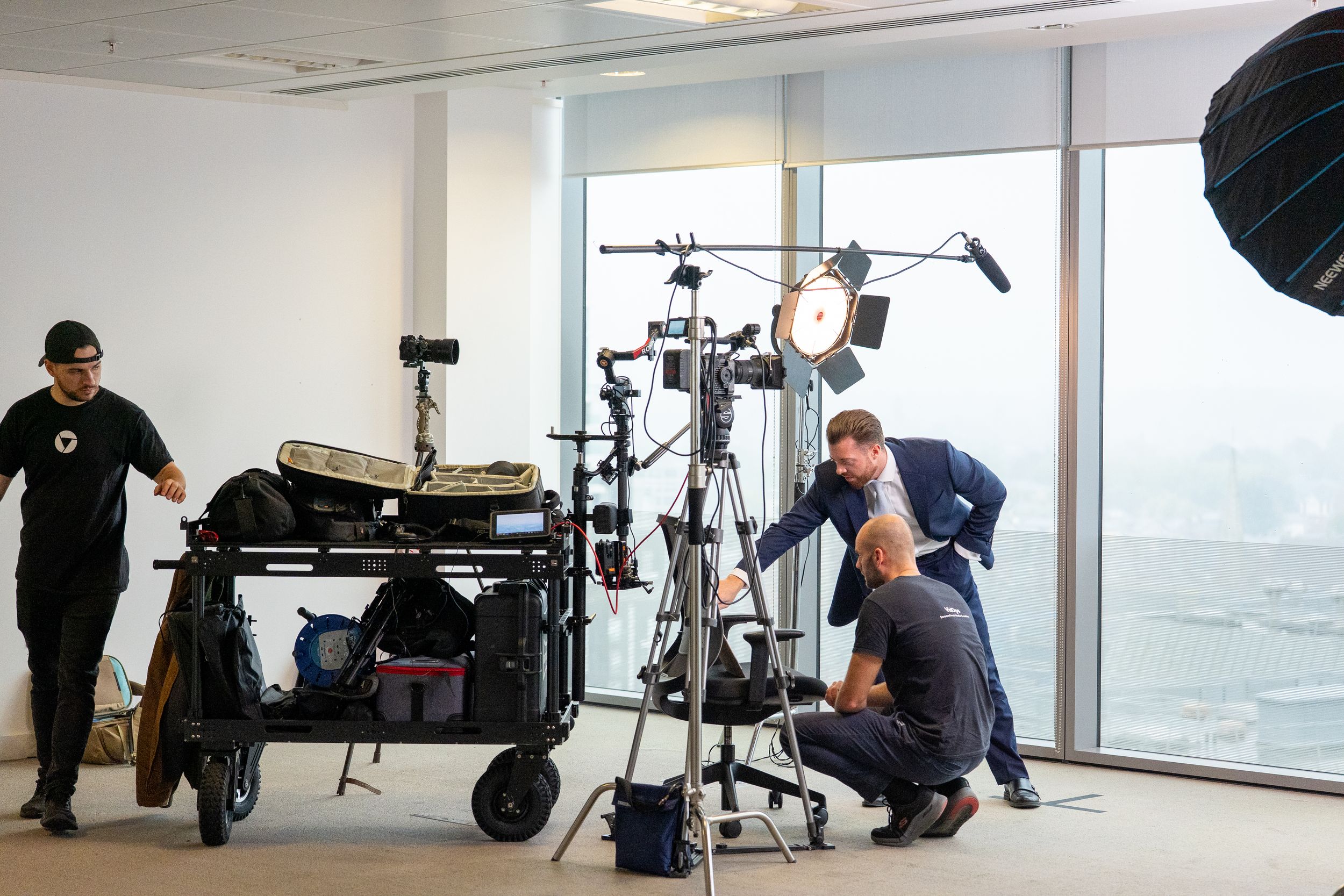 Behind-the-scenes view of video production team working with equipment in bright studio space.