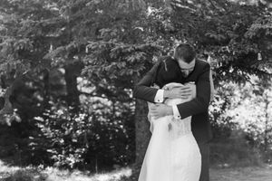 A romantic black and white wedding photo shows a couple embracing outdoors in a garden setting.