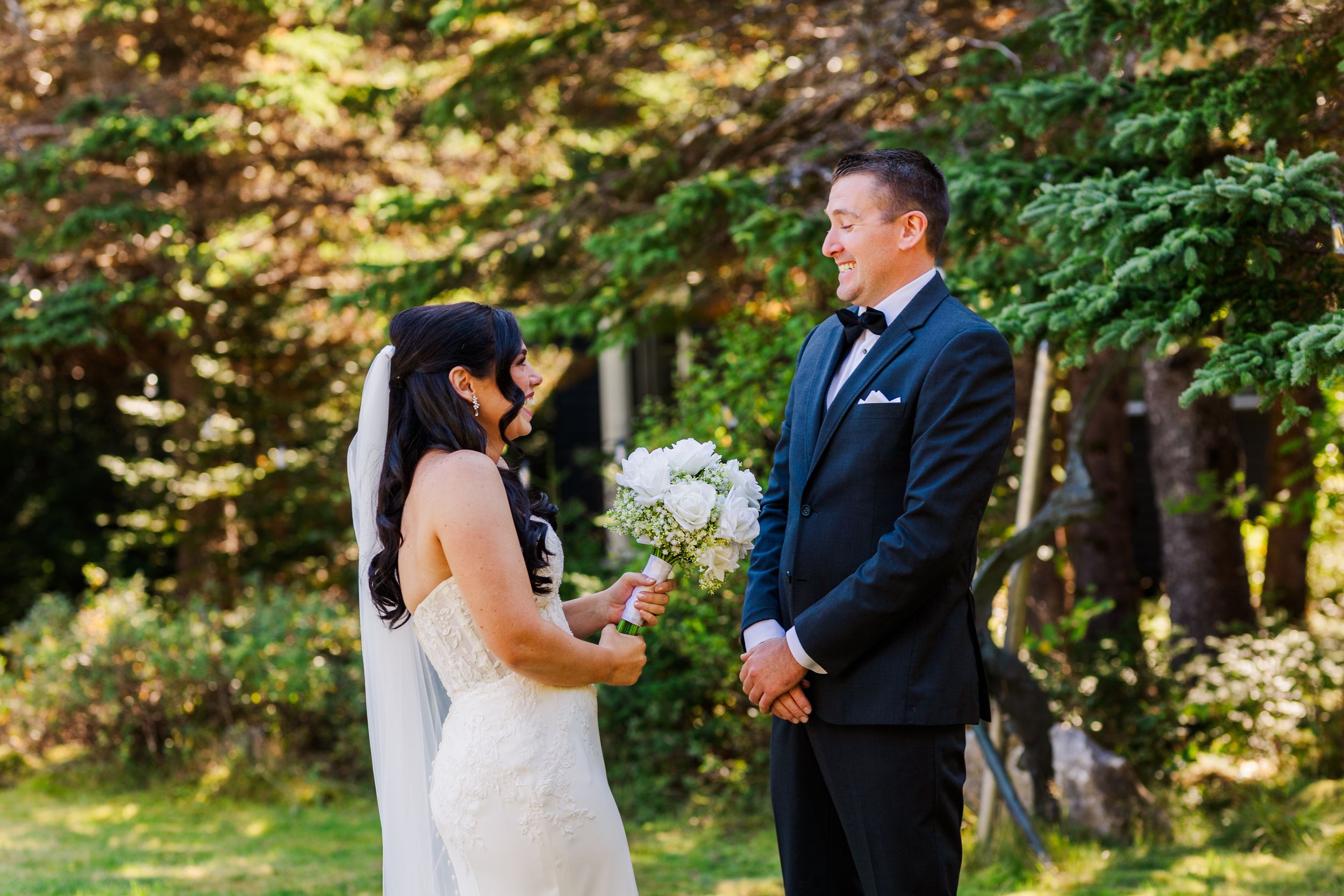 Bride and groom exchange vows during outdoor forest wedding ceremony surrounded by lush greenery.