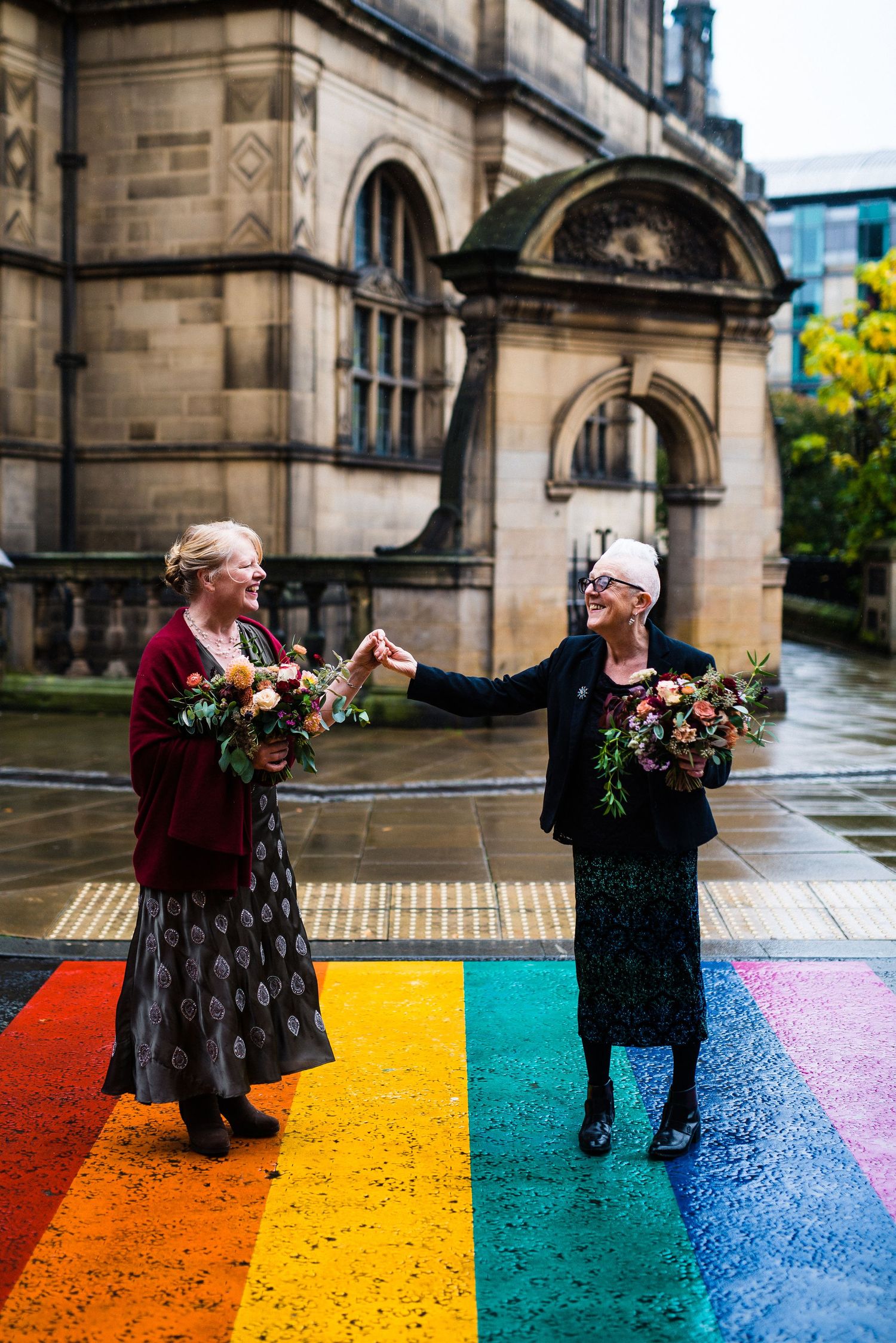 A couple dances together on a colorful painted street surface outside a historic stone church building.