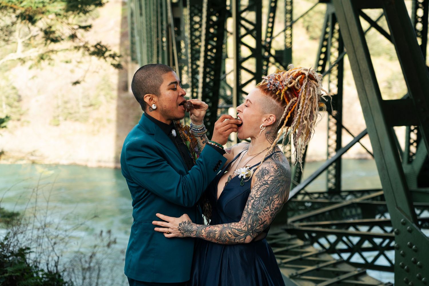 A couple shares intimate moments near a bridge during their engagement photo session in an outdoor setting. Captured by Savvy Photography