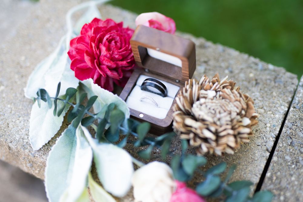 Wedding detail shot of pink roses and decorative elements on a rustic wooden surface.