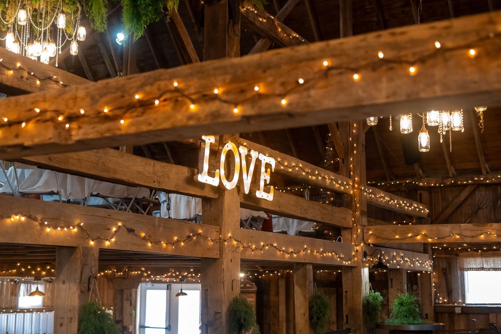 Rustic barn interior decorated with warm string lights and wooden beams.