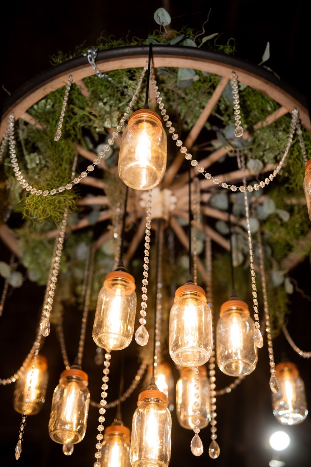 Vintage Edison bulbs and crystal decorations hanging from greenery-adorned ceiling.