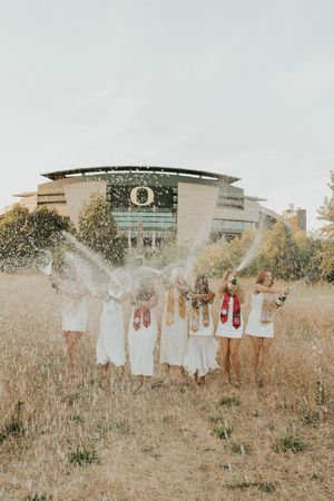 A celebratory graduation photoshoot with champagne spraying in front of the Oregon stadium.