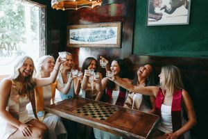 Friends gathered around wooden table in bar sharing drinks and laughter.