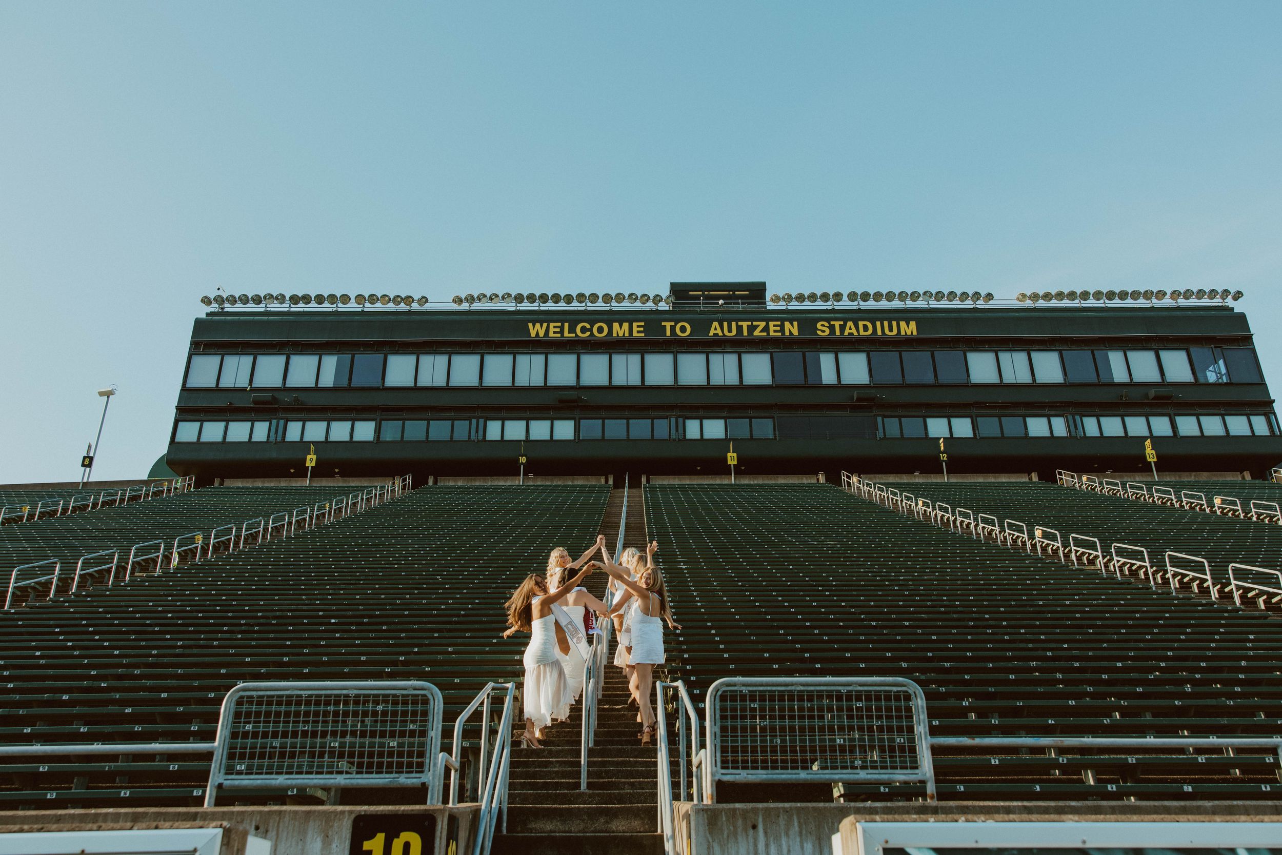 Empty stadium bleachers photographed against a bright blue sky.